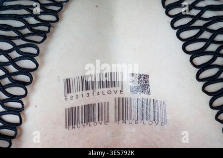 Close-up of temporary barcode tattoos spelling TRUE LOVE 20134 on pale skin. Captures ironic fusion of barcode tech and eternal love theme.   Sopot. P Stock Photo