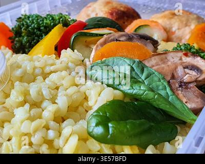 Close-up macro shot of a healthy meal prep container filled with nutritious ingredients. The foreground features fluffy cooked white rice and fresh Stock Photo
