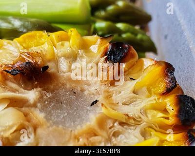 Extreme close-up macro photograph of roasted winter squash displaying caramelized and charred blackened edges. The golden-yellow flesh reveals Stock Photo