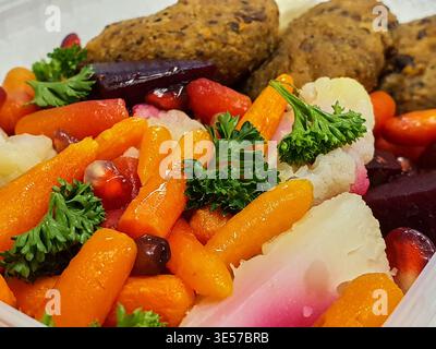 A close-up macro photograph of a colorful healthy meal served in a white container, featuring glazed baby carrots, sliced purple beets, white turnips Stock Photo