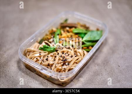A close-up photograph of a rectangular transparent plastic meal prep container placed on a gray concrete or stone surface. The container holds an Stock Photo