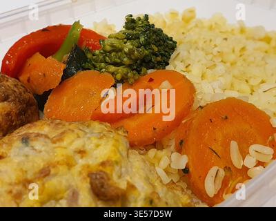 This close-up photograph shows a balanced meal served in a clear plastic takeout container. The dish features fluffy white rice accompanied by Stock Photo