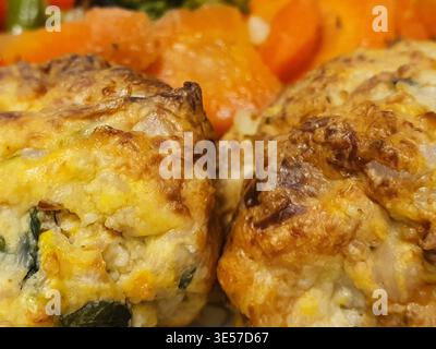 A close-up photograph of two golden-brown baked egg muffins or mini frittatas positioned in the foreground, featuring visible ingredients including Stock Photo