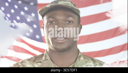 Standing man in camouflage uniform and patrol cap speaking in studio with American flag backdrop Stock Photo