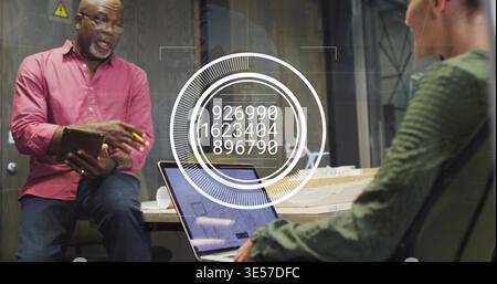 Discussing team working in glass room, wearing pink top, green sweater, laptop, tablet, model HUD Stock Photo