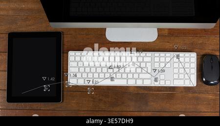 Displaying white computer keyboard centered on wood desk with monitor, tablet, mouse, data overlays Stock Photo