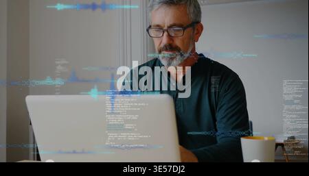 Working man wearing green henley and eyeglasses at home, coding on laptop with yellow interior mug Stock Photo