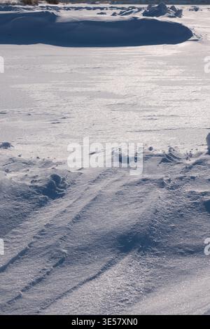 Vast winter field covered in fresh white snow with soft shadows and textured drifts under bright daylight Stock Photo