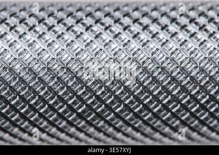 Extreme macro texture metal tool handle with knurled diamond pattern, showing industrial detail and steel surface Stock Photo