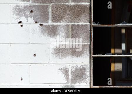 Damaged Brick Wall with Broken Window and Impact Marks Urban Decay Background Stock Photo