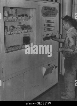 Here is Elmer, an Australian-invented electronic slot machine which can sell you anything from a ham sandwich to a box of breakfast food. The first has just completed a two month test at the CRS factory at Pyrmont. The cabinet is metal, nearly 7ft high and 5ft deep, containing shelves stocked with supplies of 25 different types of goods - packets of tea, chocolates, tinned food, sandwiches, bread rolls, biscuits,  drinks and cigarettes. Samples of each item, with prices, are on display in a lighted window. Beneath is a row of slots taking coins from ½d to 2/-. You select your goods and fe Stock Photo