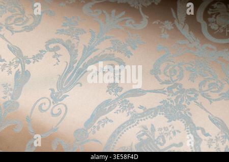 Soft beige fabric with an ornate blue damask pattern, evoking vintage elegance and romantic luxury for interiors, upholstery or wallpaper applications Stock Photo