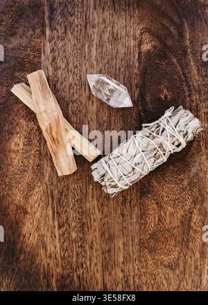 Palo santo sticks, white sage bundle and clear quartz crystal on wooden background, natural spiritual cleansing objects, minimal rustic composition. T Stock Photo