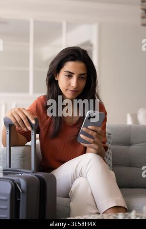 Woman using smartphone while waiting to travel Stock Photo