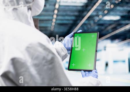 Isolated screen tablet used by hardware developer designing silicon wafers in automated manufacturing plant. Specialist inspects semiconductor substrates gear with chroma key device Stock Photo