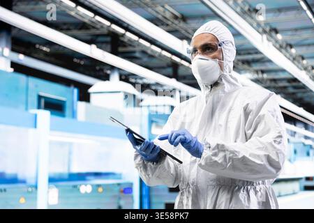 Processing silicon wafer, tablet and SOC architecture designer in automated manufacturing plant. Inspecting semiconductor substrates hardware, device and employee doing quality control Stock Photo