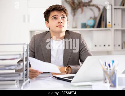 Male bookkeeper doing paperwork in workplace in office - checks accounting documents Stock Photo