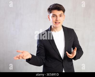 Smiling surprised young male student in suit jacket pointing at you.Portrait of guy pointing finger Stock Photo