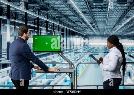 Green screen monitor, supervising semiconductors production output and man with coworker in factory. analyzing data, mockup display and specialists troubleshoot industrial plant infrastructure errors Stock Photo
