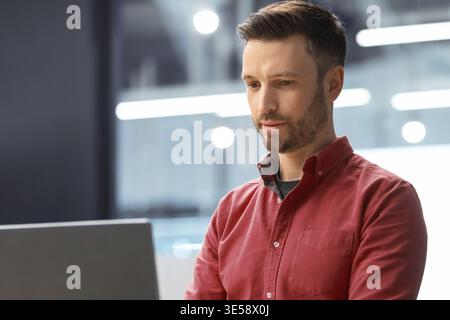 Man Using Laptop in Modern Office Setting During Work Hours Stock Photo