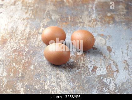Three brown eggs on an old wooden background. Stock Photo