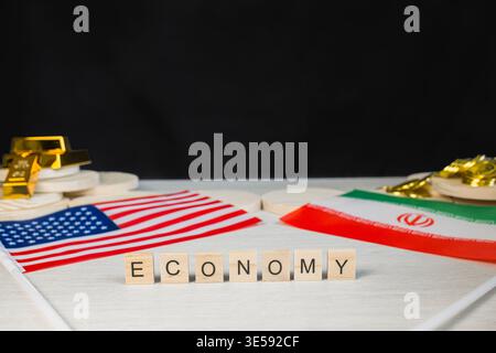 Flags of the United States and Iran flank scrabble tiles spelling ECONOMY, representing international financial relations, trade, sanctions, and resou Stock Photo