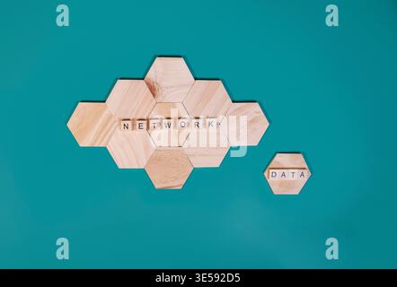 Wooden hexagon tiles spell NETWORK forming a cloud shape, with a separate DATA tile, representing information structure and digital technology concept Stock Photo