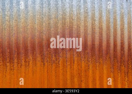 Metal surface displays a gradient of colors from gray to orange with rust. The texture is rough with vertical lines. Stock Photo