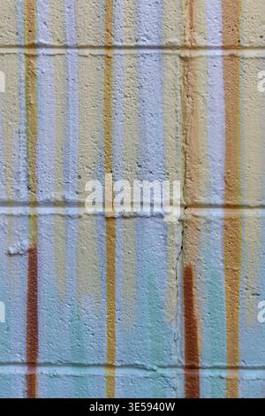 A wall shows various paint drips created by art or weather. The colors blend together, creating a textured look in a city area. Stock Photo