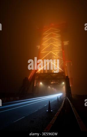 The Newport Bridge disappearing into dense fog at night with car light trails leading into mist as it crosses from Middlesbrough to Stockton-on-Tees Stock Photo