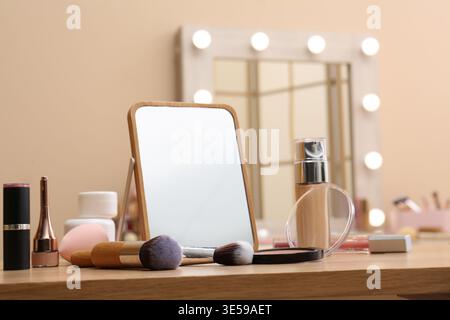Different cosmetics, makeup brushes and mirror on table in living room, closeup Stock Photo