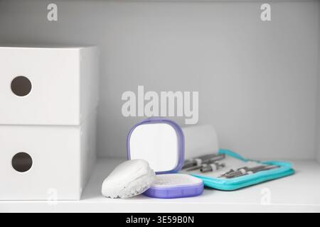 Box with occlusal splint, jaw model and tools on shelf in dentist's office, closeup Stock Photo