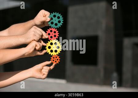 Many hands with colorful gears outdoors Stock Photo