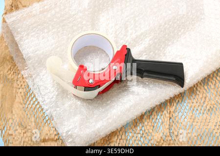 Packing tape dispenser, bubble wrap and paper on blue background Stock Photo