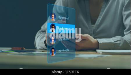 Tapping man wearing light button-up shirt using holographic contacts at desk, smartphone visible Stock Photo