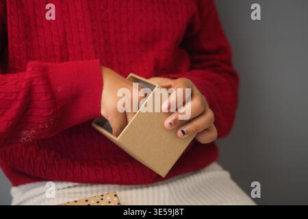 Child opens small box with hands in indoor setting Stock Photo