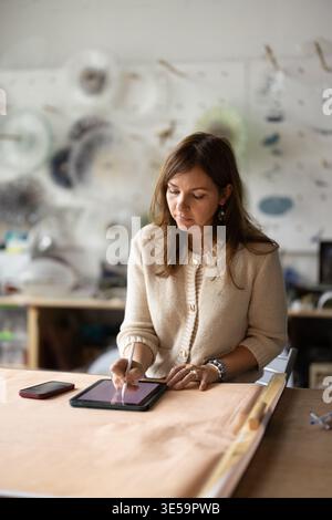 Craftswoman working in creative studio, using application on digital tablet Stock Photo