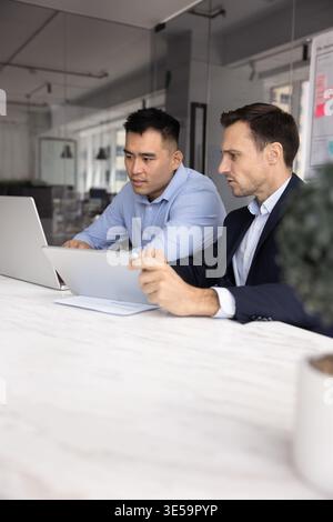 Two multicultural businessmen colleagues developing project using digital tablet notebook Stock Photo