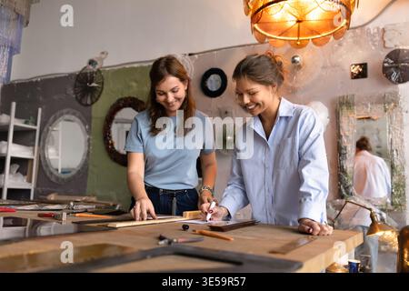 Craftswomen colleagues collaborating on glass work design Stock Photo