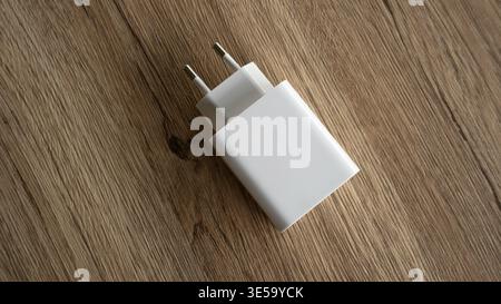 White Universal European Power Adapter Plug on Brown Wooden Background Stock Photo