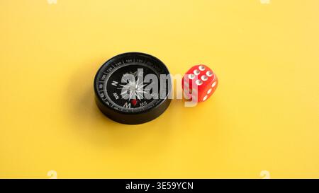 Black Magnetic Compass and Red Dice on Bright Yellow Background for Travel Concept Stock Photo