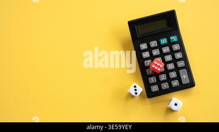Red and White Dice with Black Electronic Office Calculator on Yellow Surface Stock Photo