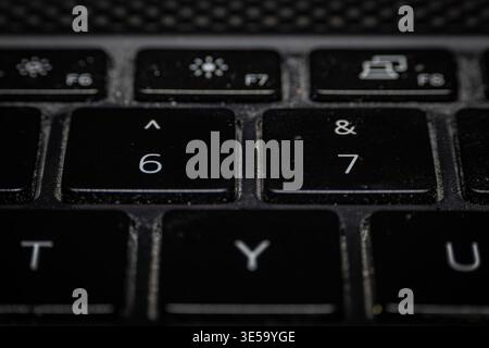 Macro close-up of a dusty black computer keyboard focusing on the adjacent 6 and 7 number keys with functional icons in the top row Stock Photo