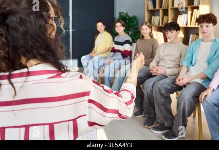 Teacher leading teen students in group counseling session inside library classroom Stock Photo