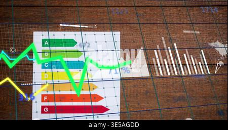 Displaying energy chart sitting left on wood table, with neon yellow lines, white bars, faint grid Stock Photo
