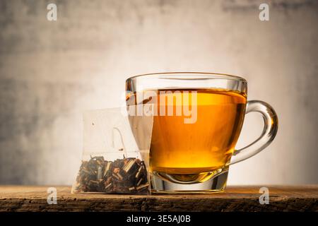 Glass cup of tea on wooden table with tea bag. Stock Photo