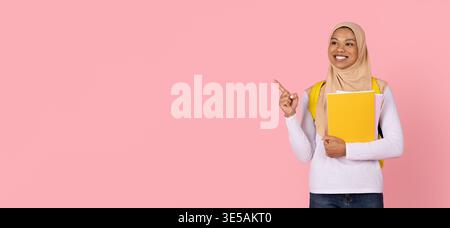 Young black Muslim woman student in hijab pointing at copy space Stock Photo