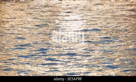 Golden hour light reflecting on rippling water surface creating sparkling texture Stock Photo
