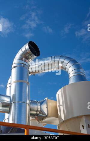 Industrial ventilation system with galvanized steel ductwork and metal exhaust pipes against a blue sky, air filtration and grain dust extraction Stock Photo