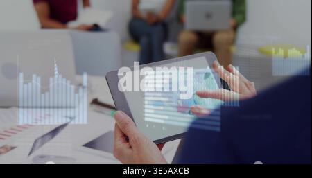 Holding tablet, adult hands tapping charts in office lounge, colleagues in casual business clothes Stock Photo